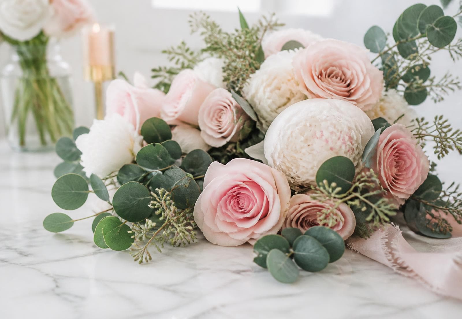 Arranjo de rosas cor de rosa e folhagens sobre mármore